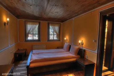a bedroom with a large bed with two windows at Gozbarov's Guest House in Koprivshtitsa
