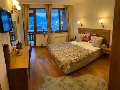 a bedroom with a large bed and a large window at Rodope Nook Guest house in Chepelare