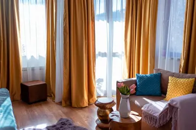 a living room with yellow curtains and a couch at Rodope Nook Guest house in Chepelare