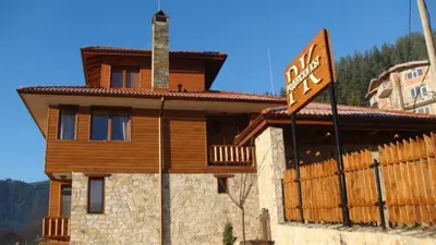 a wooden house with a street sign in front of it at Rodope Nook Guest house in Chepelare