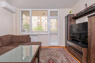 a living room with a couch and a flat screen tv at Comfortable One Bedroom Apartment in a Lively Area | Zona B5 | Russian Square in Sofia
