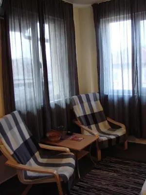two chairs and a table in a room with windows at Avel Guest House in Sofia