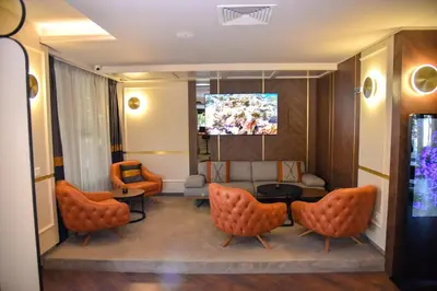 a waiting room with orange chairs and a tv at Park Hotel Plovdiv in Plovdiv