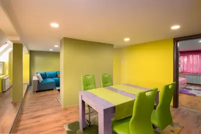 a dining room with a table and green chairs at Serdika Round Tower Apartments in Sofia
