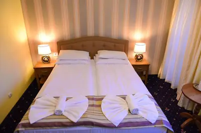 a bedroom with two beds with white sheets and pillows at Family Hotel Lazur in Bansko