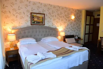 a bedroom with a large bed with white sheets and pillows at Family Hotel Lazur in Bansko