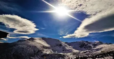 a sun shining over a snow covered mountain at Vila Rila Samokov in Samokov