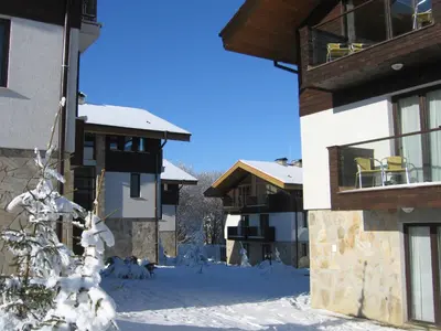 a snow covered yard in front of a building at Chamkoria Chalets in Borovets