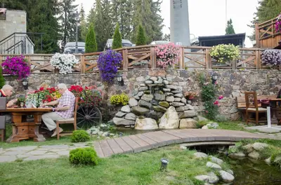 a man sitting at a table in a garden with flowers at Complex Kamelia in Pamporovo