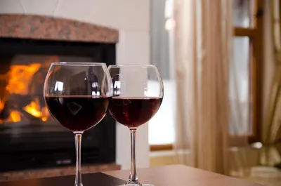 two glasses of wine sitting on a table in front of a fireplace at Complex Kamelia in Pamporovo