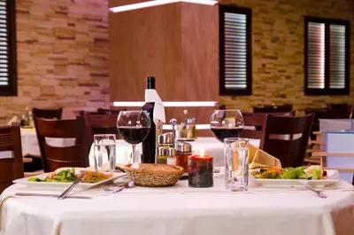 a table with two plates of food and wine glasses at Complex Kamelia in Pamporovo