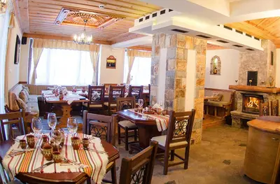 a restaurant with tables and chairs and a fireplace at Complex Kamelia in Pamporovo