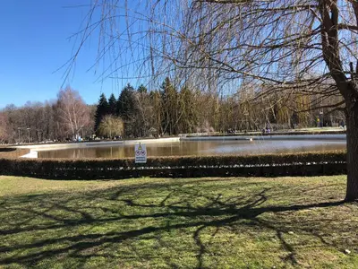 a park with a pond and a tree and a sign at Center apartment with amazing view in Sofia