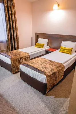 two beds in a hotel room with yellow pillows at Eleganza Family Hotel - Free Parking in Sofia