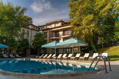 a hotel with a swimming pool with chairs and umbrellas at Family Hotel Edia-Sandanski in Sandanski