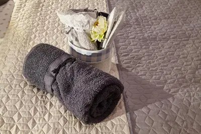 a gray towel on a bed with a flower at City Center Studio in Plovdiv