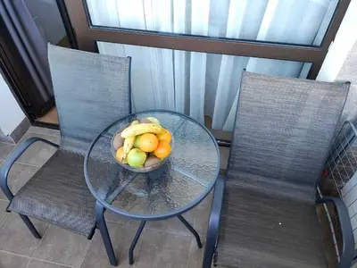 a bowl of fruit on a glass table with two chairs at Aspen Golf and Ski Resort in Bansko
