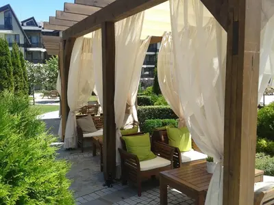 a group of chairs under a pergola with white curtains at Aspen Golf and Ski Resort in Bansko