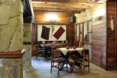 a restaurant with wooden walls and tables and chairs at Guest House Dzhangal in Bansko