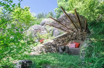 a stone building with a bed in the grass at Omaya Eco Village in Gaytaninovo