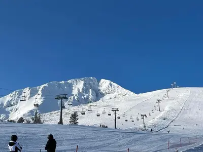 two people on a snow covered ski slope with a ski lift at Dedo Pene Inn in Bansko