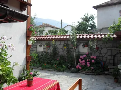a garden with flowers and a stone wall at Family Hotel Nadejda in Bansko