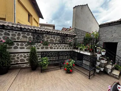 a balcony with a bench and potted plants and a building at Durchova Kashta Family Hotel in Bansko