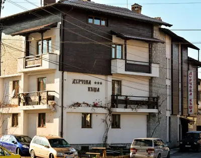 a building with cars parked in front of it at Durchova Kashta Family Hotel in Bansko