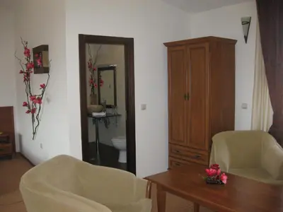 a living room with two chairs and a table and a cabinet at Molerite Complex in Bansko
