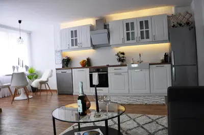 a kitchen with white cabinets and a table with a bottle of wine at Lux Apartment in Pazardzhik