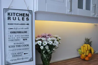 a vase of flowers and a sign that reads kitchen rules at Lux Apartment in Pazardzhik