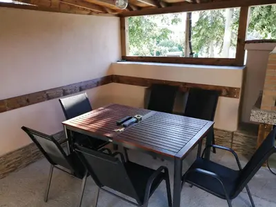 a wooden table and chairs in a room with a window at Къща за гости Мира in Strelcha