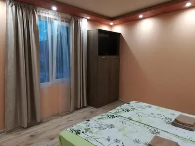 a bedroom with a bed and a tv on the wall at Къща за гости Мира in Strelcha