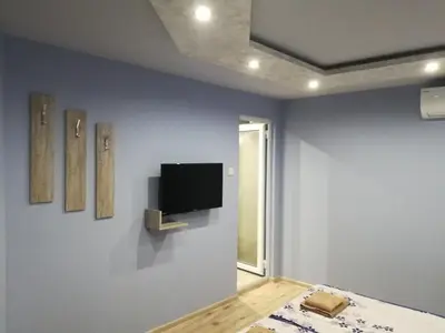 a room with a tv on a blue wall at Къща за гости Мира in Strelcha
