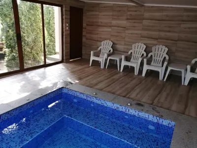 a room with a swimming pool with chairs and a table at Къща за гости Мира in Strelcha