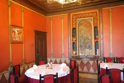 a room with a table with red chairs and a painting at Hotel Alafrangite in Plovdiv