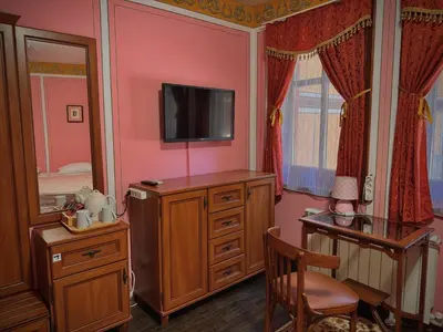 a bedroom with a tv on a dresser and a desk at Family Hotel at Renaissance Square in Plovdiv