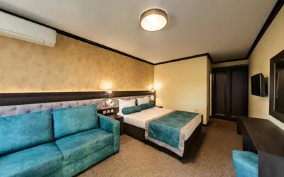 a hotel room with a bed and a couch at Family Hotel Bunara in Brestnik