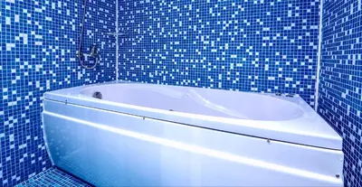 a blue tiled bathroom with a white bath tub at Family Hotel Dalis in Sofia