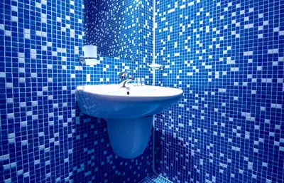 a blue tiled bathroom with a sink in it at Family Hotel Dalis in Sofia