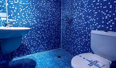 a blue tiled bathroom with a toilet and a sink at Family Hotel Dalis in Sofia