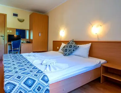 a bedroom with a large white bed with blue and white sheets at Family Hotel Dalis in Sofia