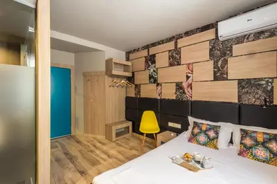 a bedroom with a bed and a yellow chair at Hotel Allur in Plovdiv