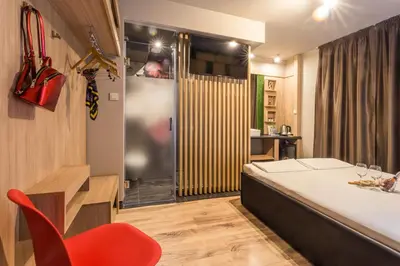 a room with a bed and a red chair at Hotel Allur in Plovdiv