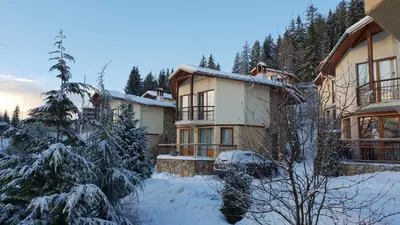 a house in the snow with a car parked in front at Amampuri Village in Pamporovo