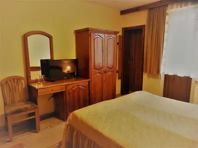 a bedroom with a bed and a desk with a television at Boyadjiyski Guest House in Bansko