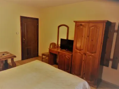 a bedroom with a bed and a wooden cabinet at Boyadjiyski Guest House in Bansko