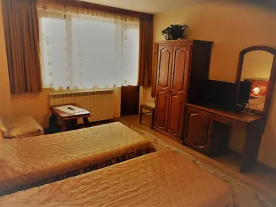 a bedroom with two beds and a television and a dresser at Boyadjiyski Guest House in Bansko