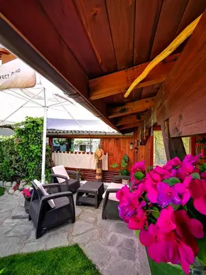 a patio with a bunch of chairs and pink flowers at Zigen House in Bansko