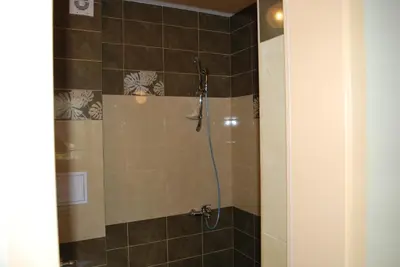 a bathroom with a shower with brown tiles at Hotel Milenium in Sofia
